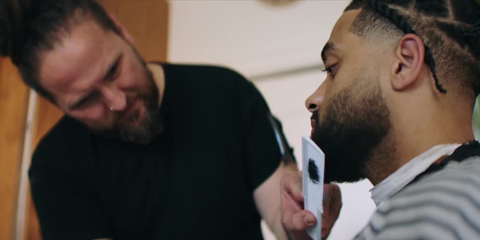 Barber combs and trims the beard of a customer
