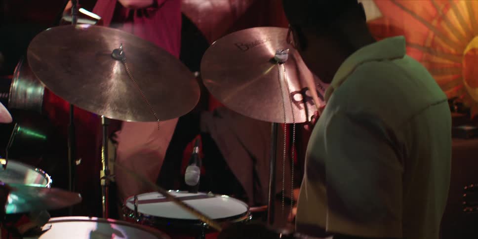 Members of a band are playing musical instruments on a stage