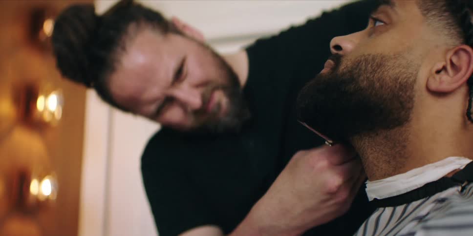 Barber combs and trims the beard of his client