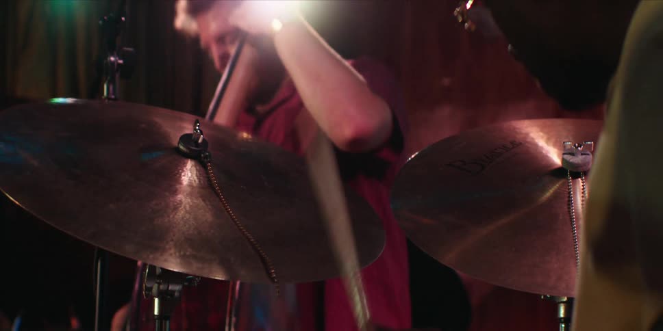 Two men in a room playing drums and guitar