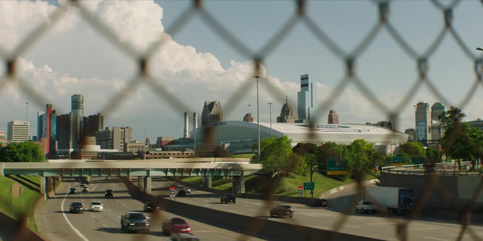 View through a metal railing of an overpass with traffic and skyscrapers of a metropolis in the background
