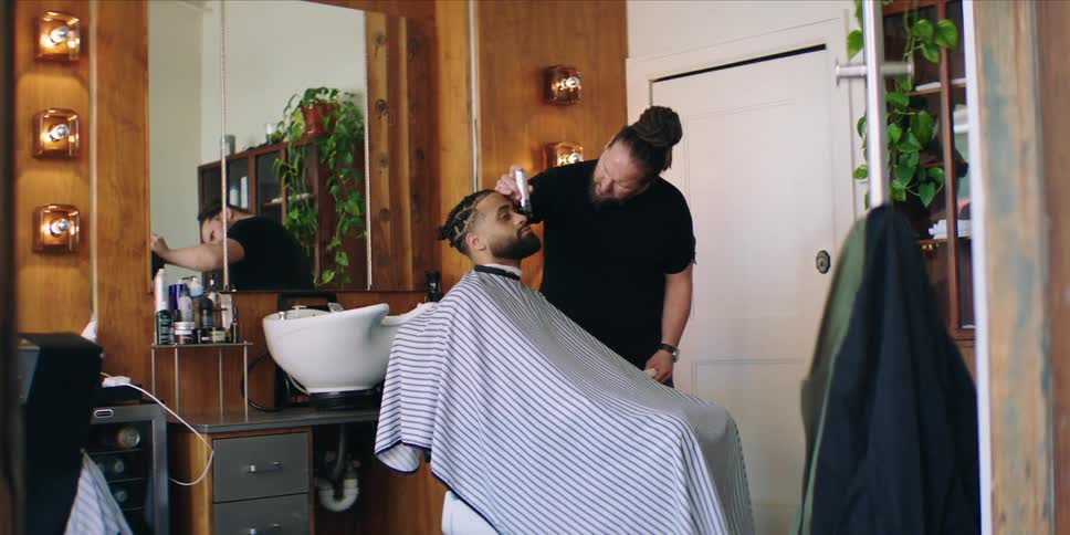 A barber is shaving a customers beard