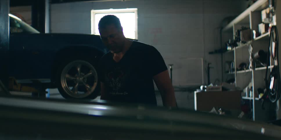 Car mechanic examines a car while working in a commercial car garage