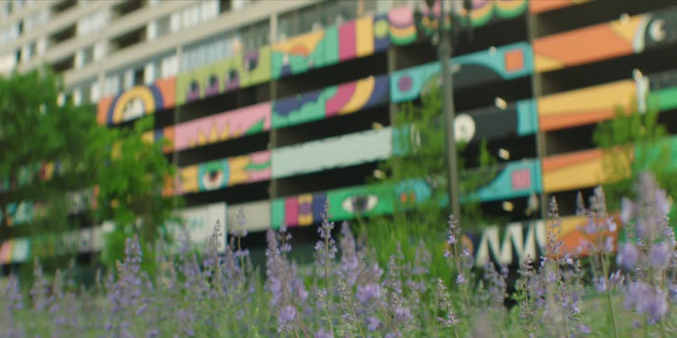 A residential building with artistic designs on its wall surrounded by lush green vegetation