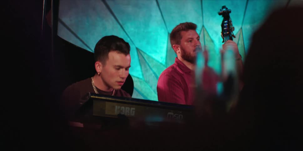 A man playing a keyboard and nodding his head and another man playing a cello