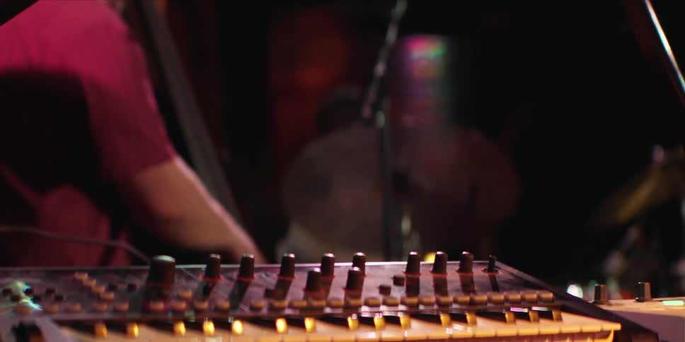 Men are playing instruments close together in a darkened room