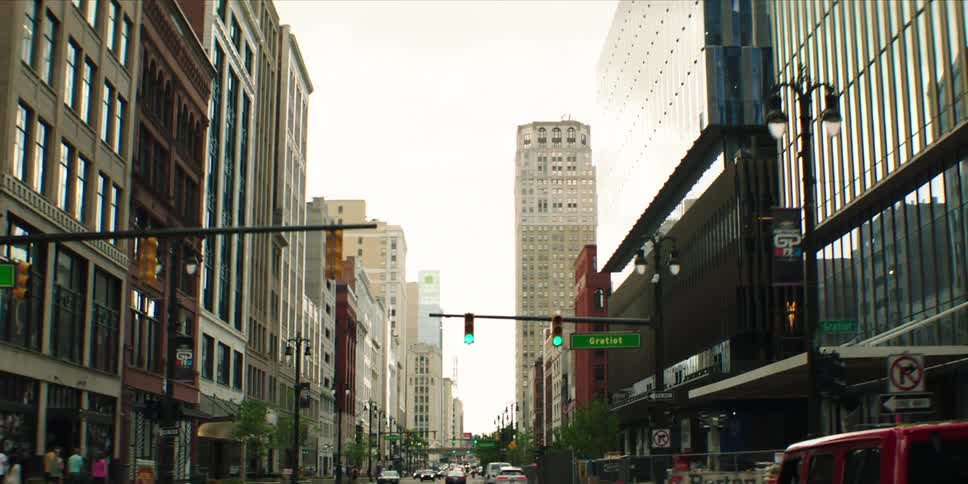Busy downtown street lined with tall buildings and traffic lights under daylight