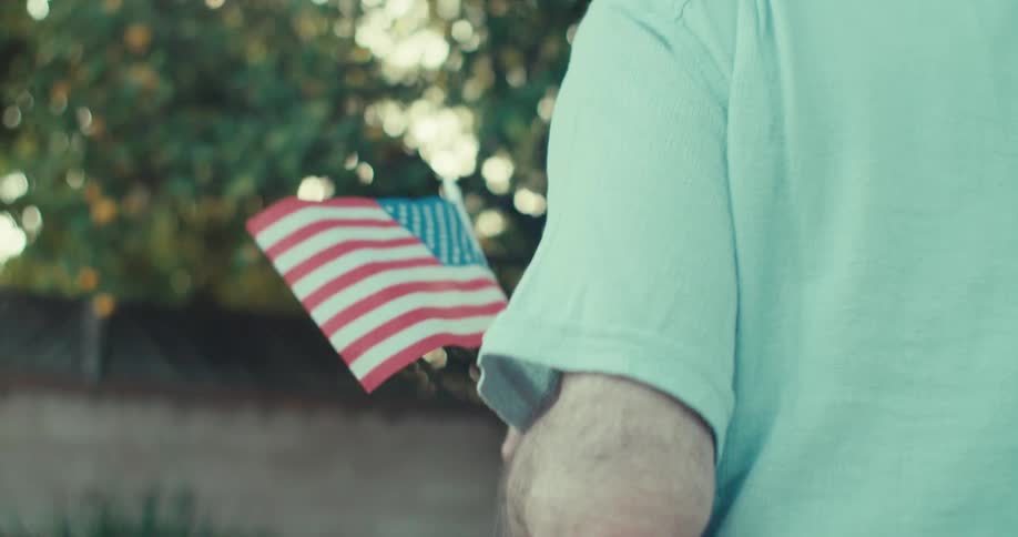 A man is holding an american flag in his yard