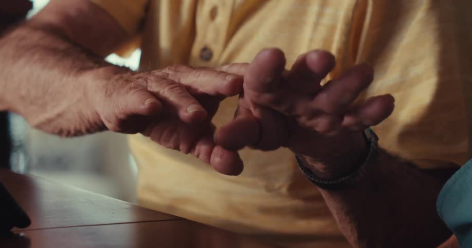 An elderly man dancing with his hands in front of a tablet placed on a table