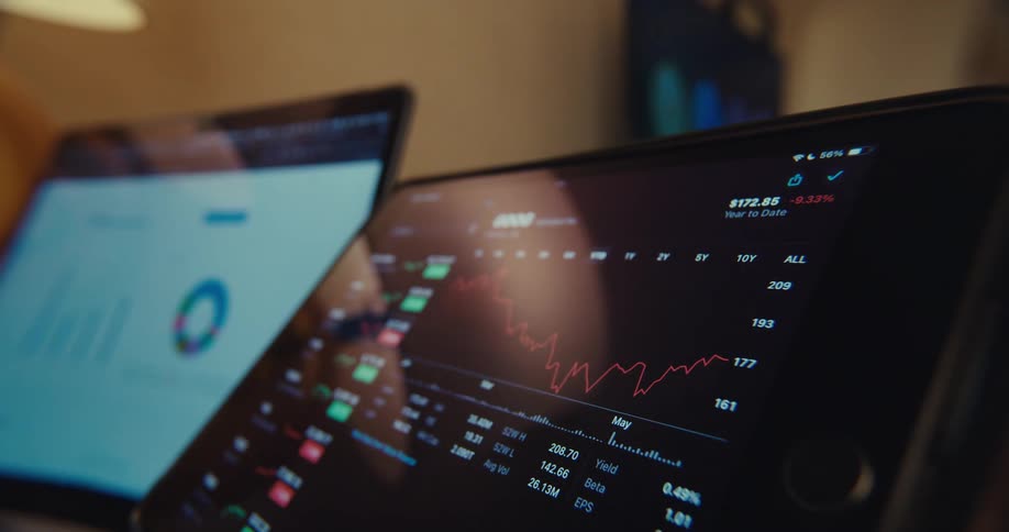 Two monitors are placed side by side with one displaying a stock chart