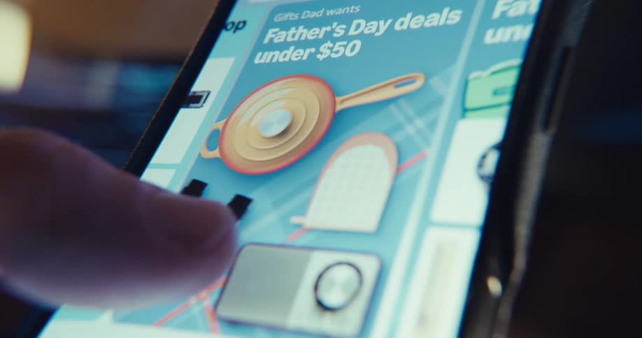 A finger is browsing over the screen of a smartphone displaying a shopping app with various deals
