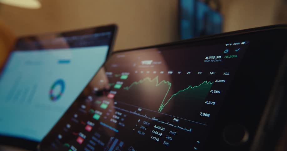 Closeup of digital stock market charts and analytics on multiple screens