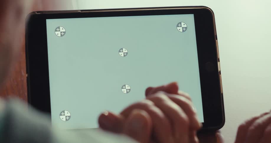 A person is holding an elderly womans hand as they look at a tablet