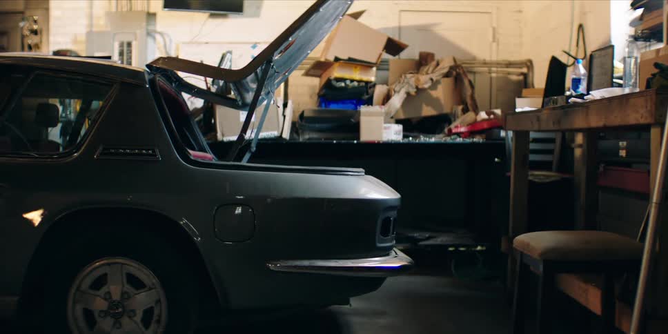 A vehicle is parked inside a garage with its hood open