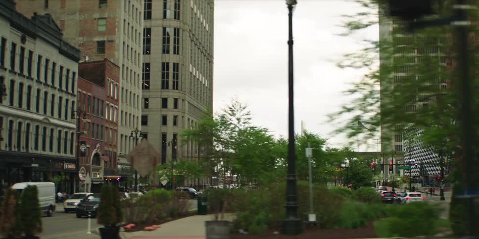 A moving vehicle captures a busy urban street scene with cars buildings and pedestrians