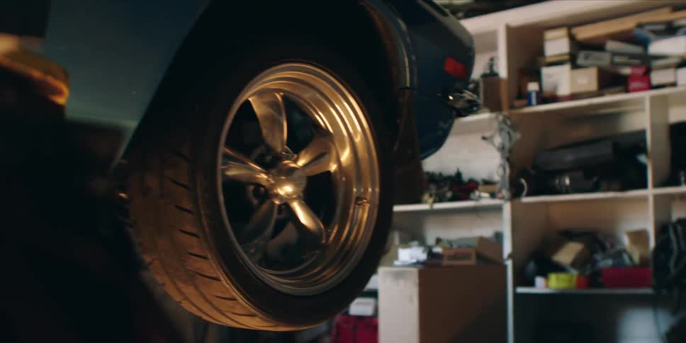 A closeup shot of a car wheel elevated in a cluttered garage or workshop