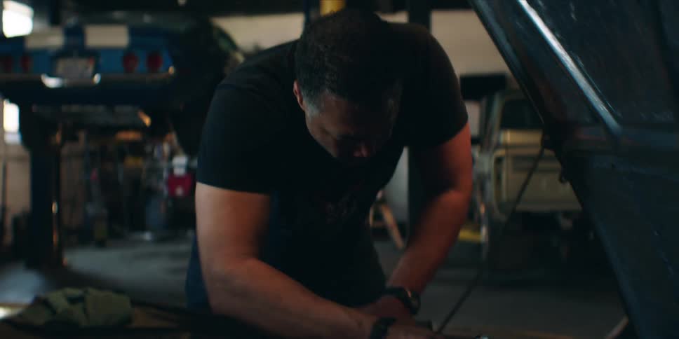 A man in a repair shop fixing a car engine