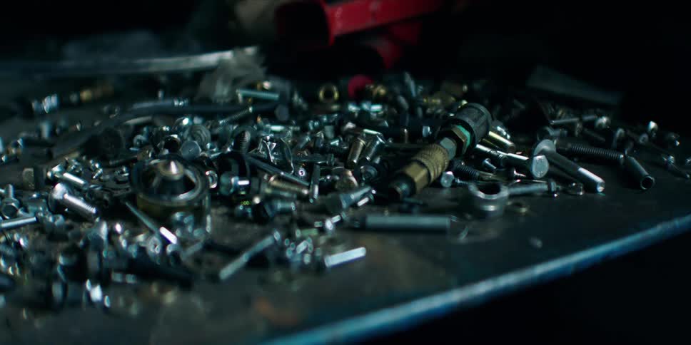 A cluttered workbench covered in scattered screws bolts and mechanical parts