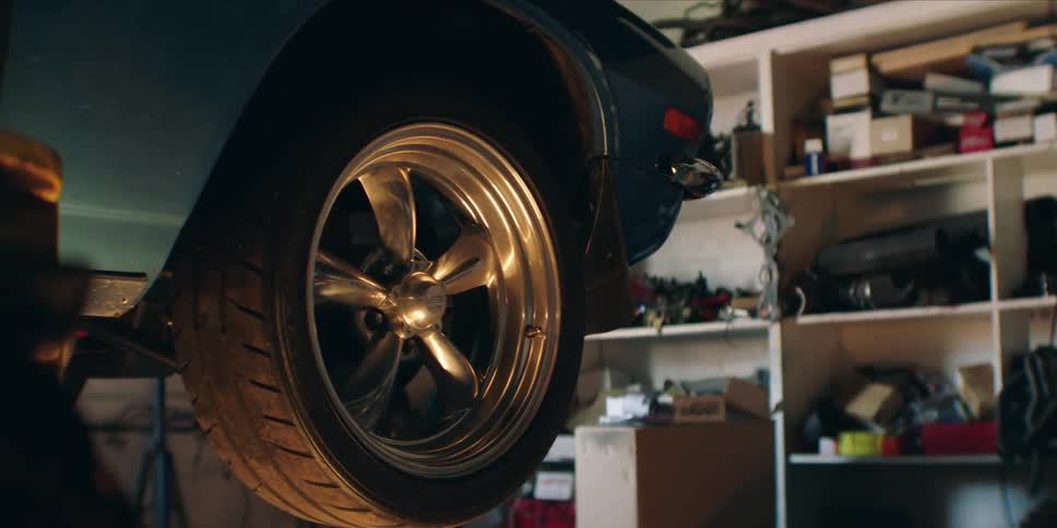 Car in a garage lift hangs in the air near cluttered shelves