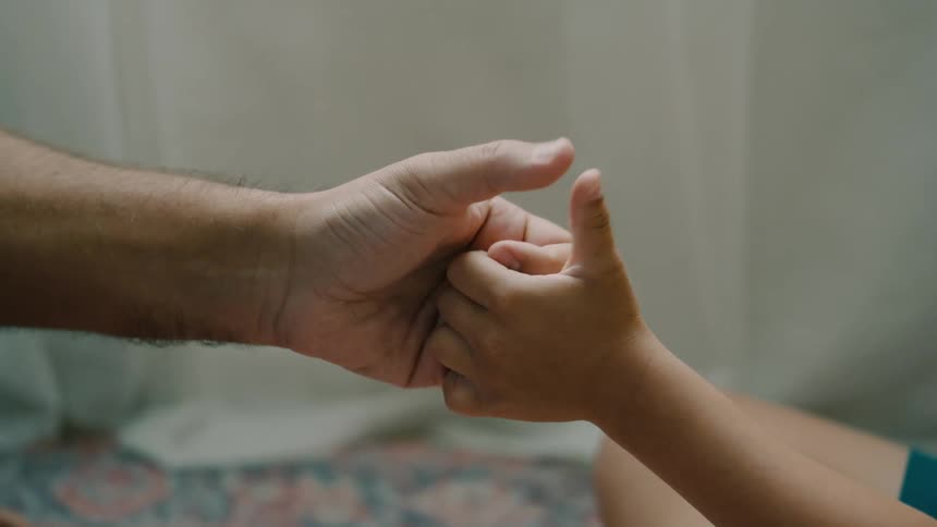 Father and son sitting on the carpet thumb wrestling