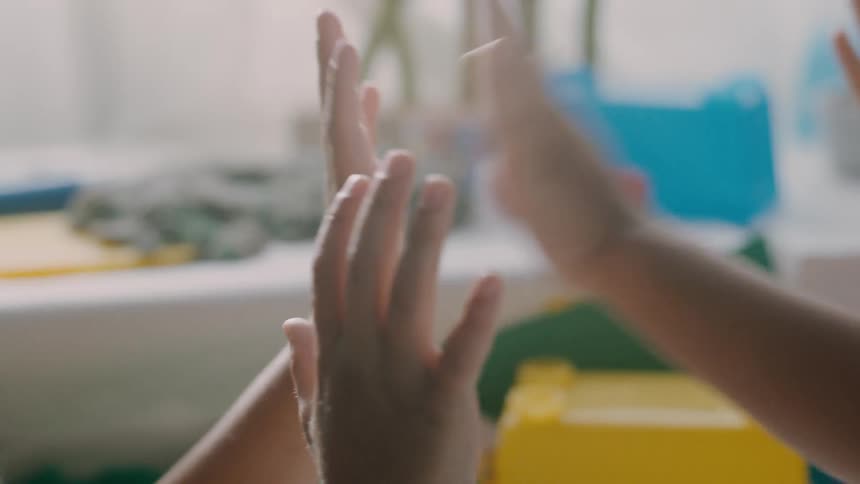 Pair of childs hands held up as thier friend teaches them to play patty cakes