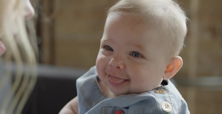 A baby smiles and laughs as a person gets closer to it