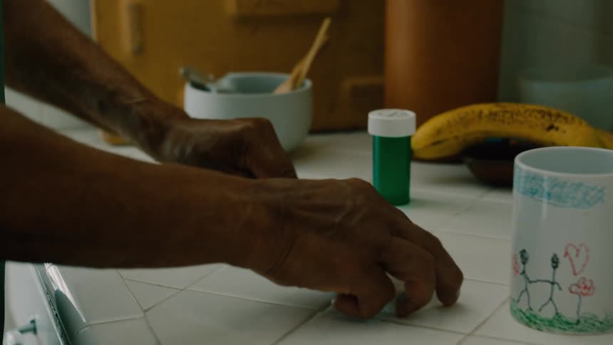 Man standing in his kitchen takes his medication