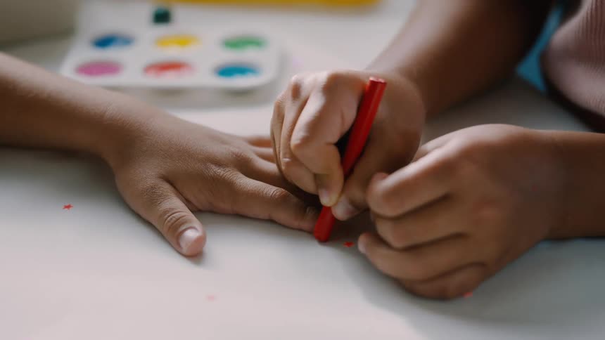 A child traces the hand of another child