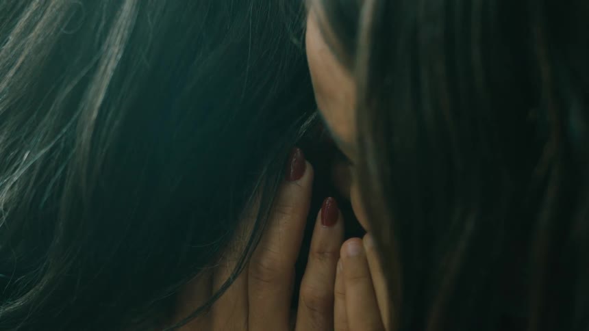 Daughter whispering and laughing into mothers ear in a closeup