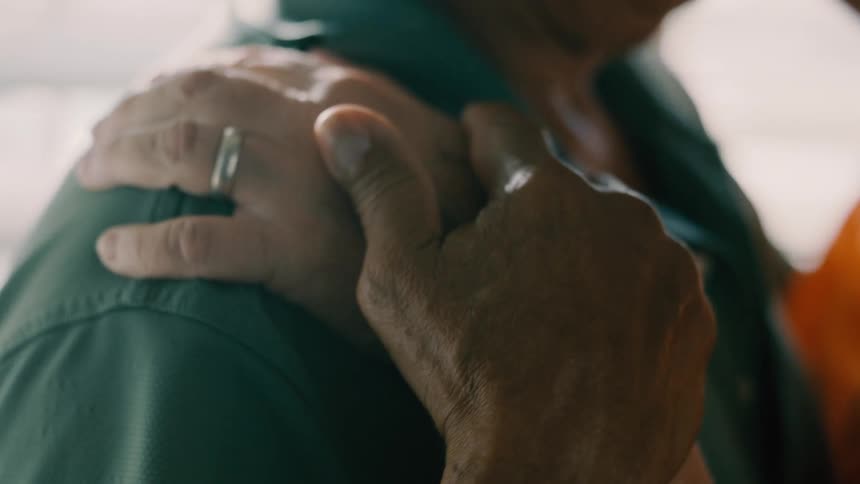 Close up of a couple holding hands while dancing slowly in a room