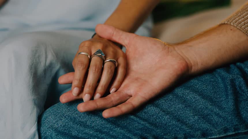 Closeup of man and woman holding hands in a romantic war setting