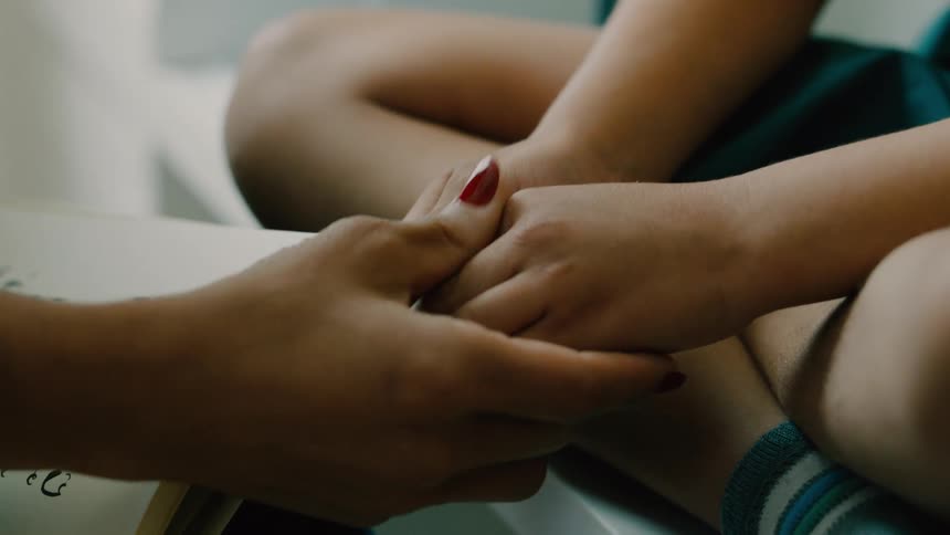 A mother rubs her sons hand