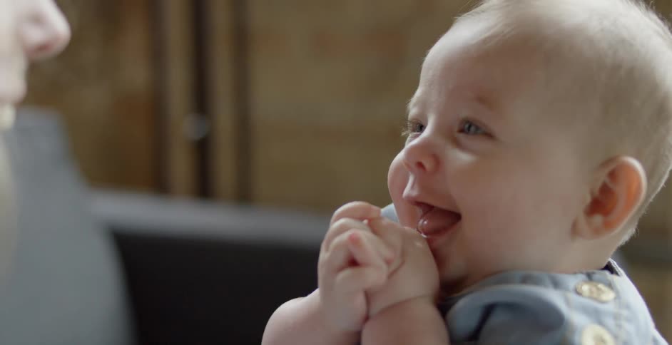 A woman holds a baby on a couch