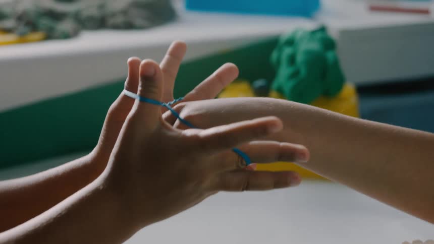 Two children are playing with a rubber band