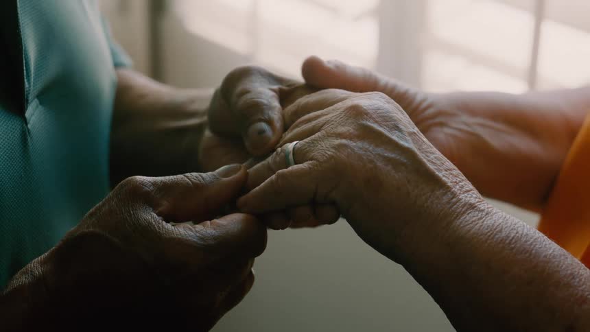 A closeup shot captures two hands one with a ring gently clasped together