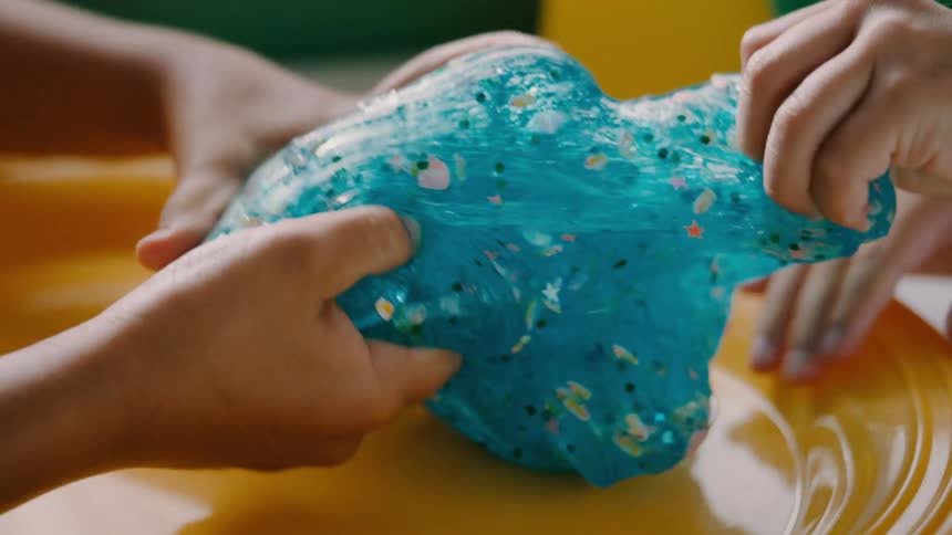 Two children pull and play with glitter filled slime