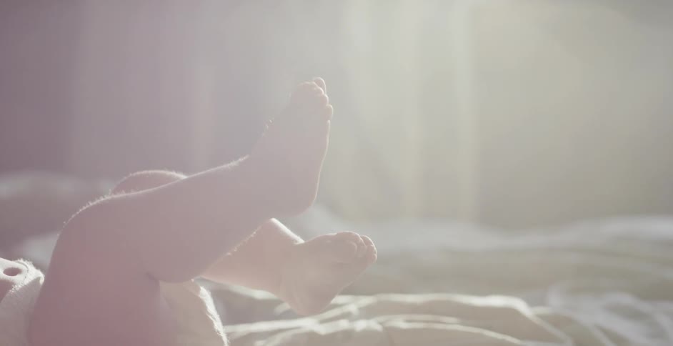 A baby lays with its feet in the air