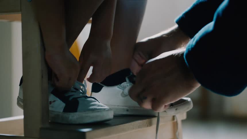 A mother ties her sons sneakers