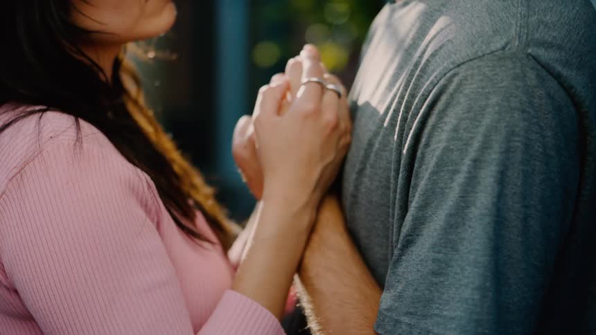 A woman puts her hands on a mans shoulder and dances with him