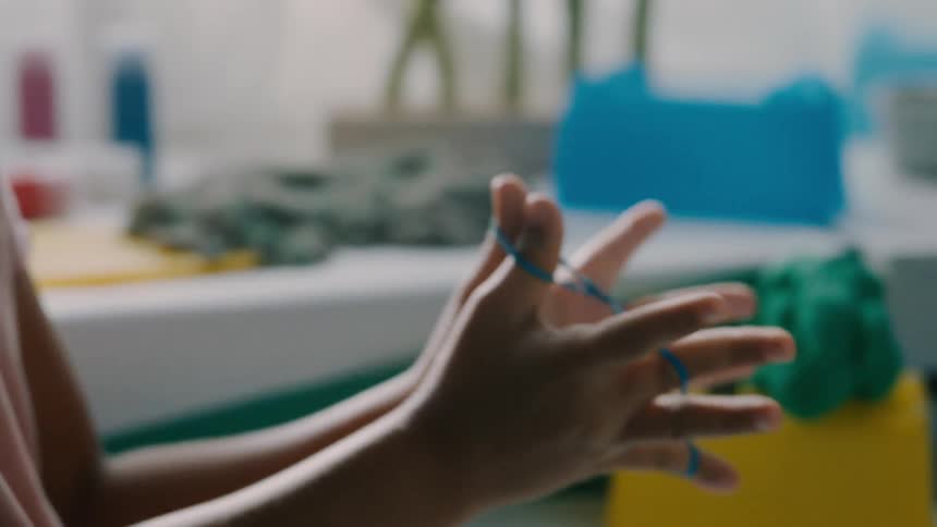 A childs hands are playfully stretching and twisting rubber bands on their fingers