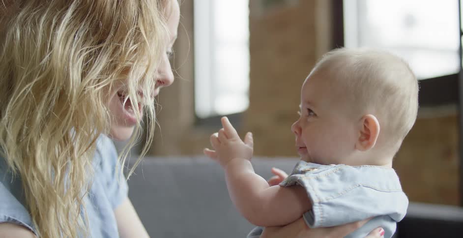A woman laughs and smiles playfully with a baby