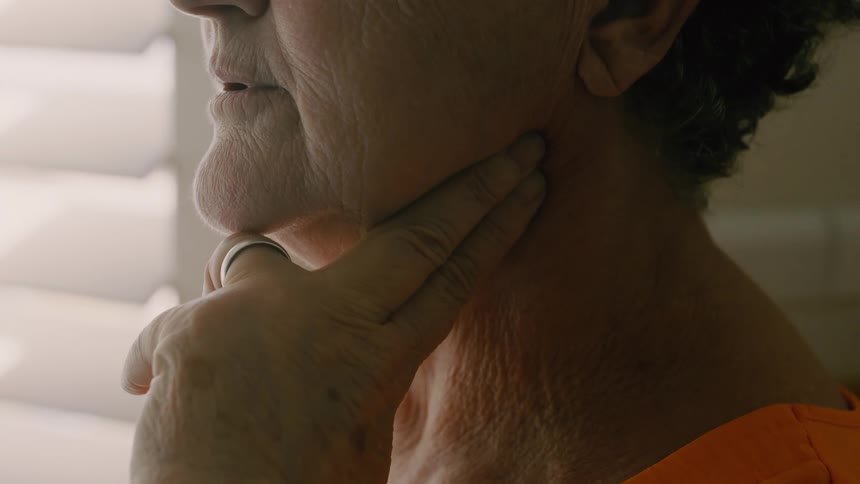 Close up of elderly woman taking steady breaths as she checks her carotid pulse with her middle and index fingers