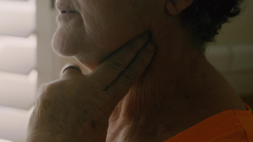Close up of an elderly womans neck as she checks her pulse with her index and middle fingers while steadying her breathing