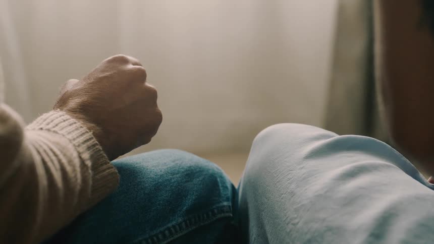 Close up of woman withdrawing her hand away from her partner as he is about to touch her as they are seated