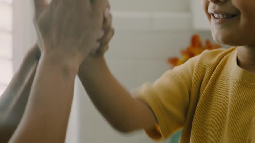 Close up of mother and daughter smiling while playing and demonstrating hand games in a room