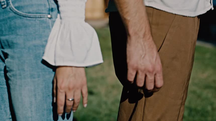 Man moves his drink from his hand so that he and his significant other can brush hands