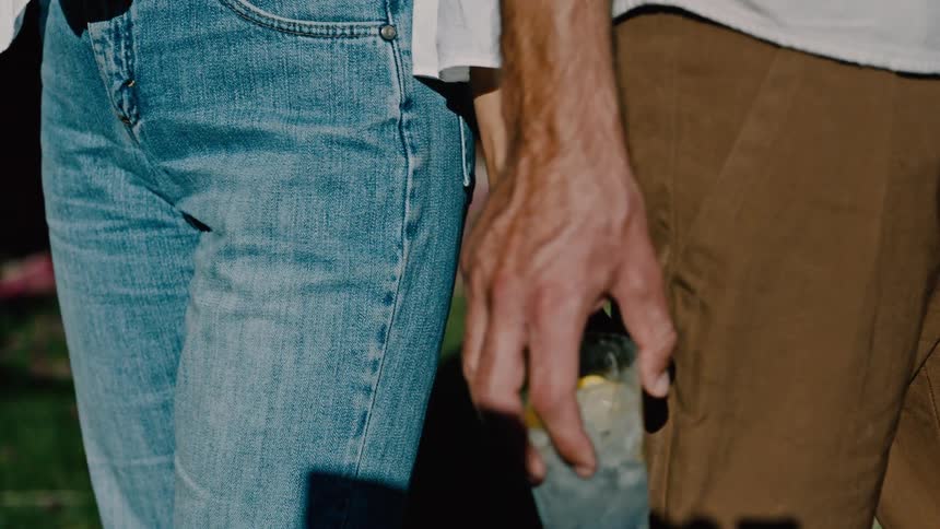 A man holding a glass of drink stands under the sun beside a woman