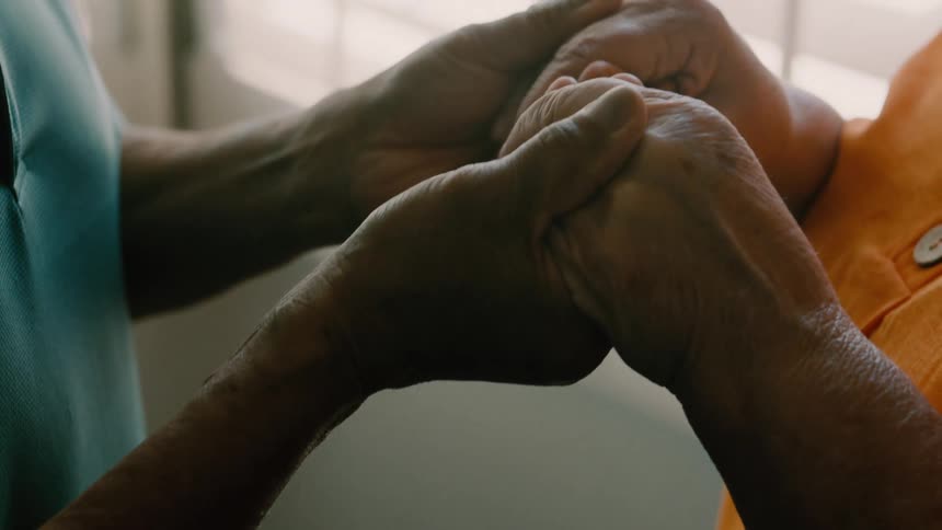 Close up of an elderly couple holding hands while standing in a room