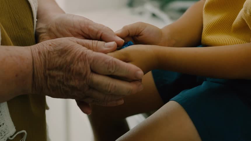 A grandmother hands her grandson a toy
