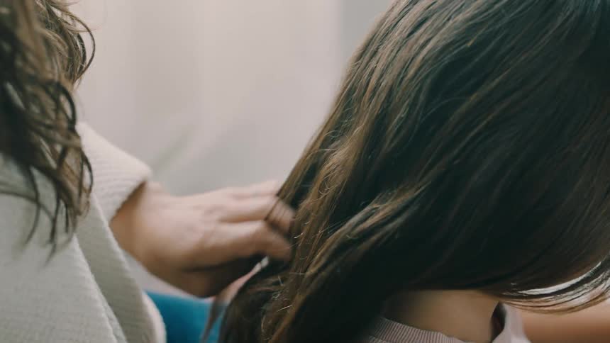 Mother braiding her daughters long thick hair